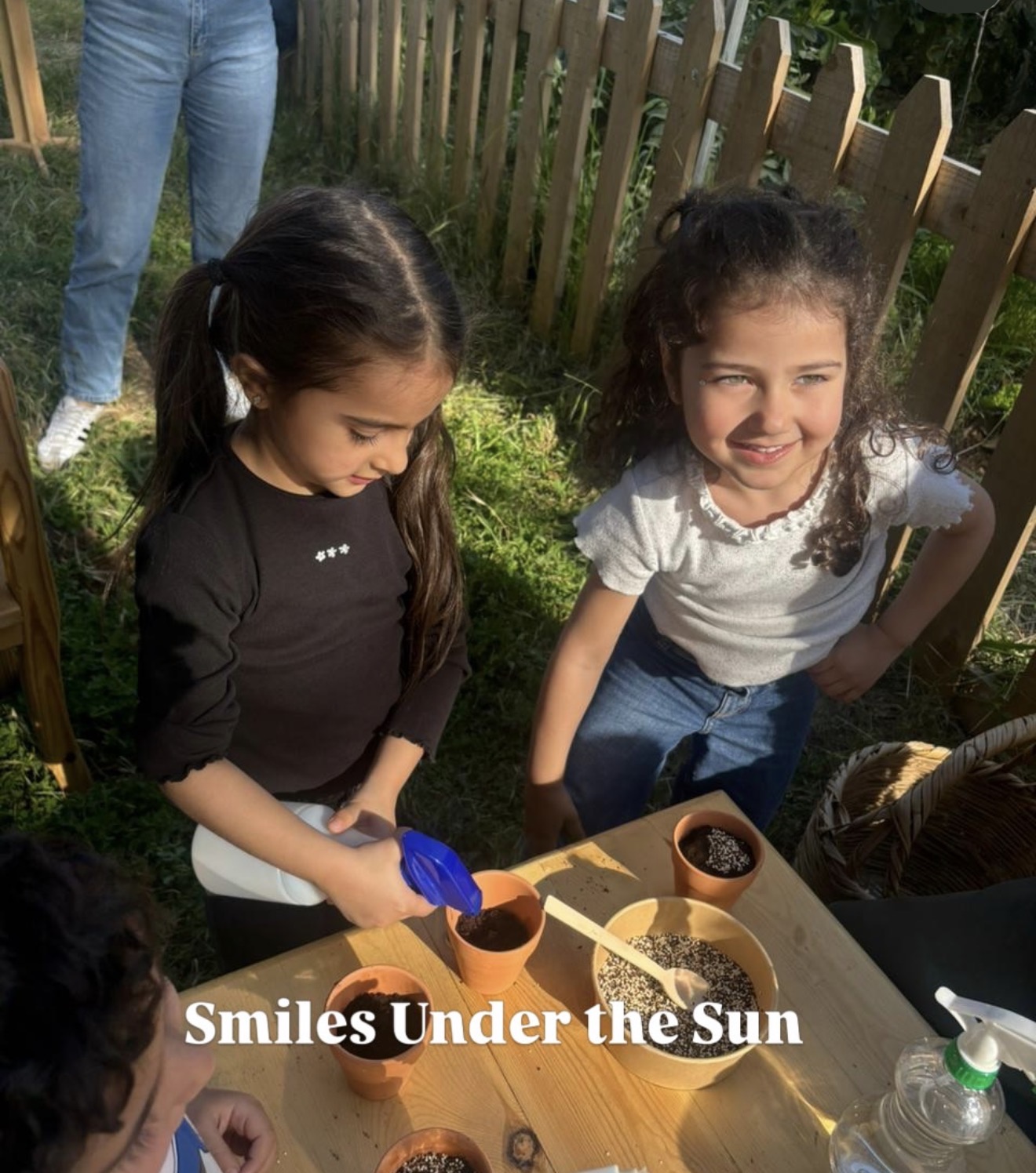 Two smiling girls planting seeds in the sun